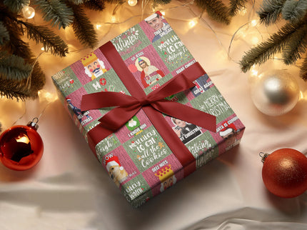 Ein quadratisches Weihnachtsgeschenk, eingepackt in buntem Papier mit humorvollen Motiven und Zitaten, ist mit einer roten Schleife verziert. Das Geschenk liegt unter einem Weihnachtsbaum mit Lichtern und Kugeln.
