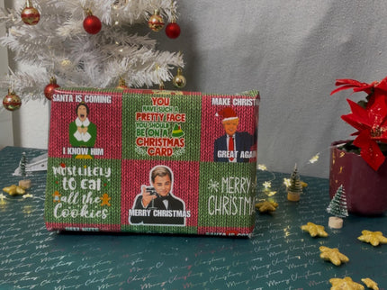 Auf dem Bild ist ein in Meme-Weihnachtspapier verpacktes Geschenk vor einem weißen, geschmückten Weihnachtsbaum. Auf dem Geschenk sind humorvolle Aufdrucke mit Weihnachtsmotiven und bekannten Figuren zu sehen.